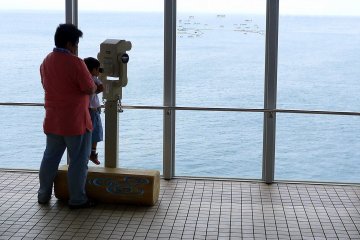 Father helping his tiny son look through the telescope