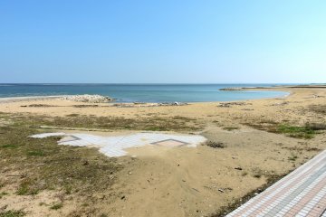 A paved promenade gives way to a sandy beach