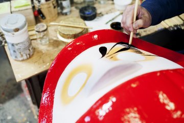 Melukis detil di atas boneka Daruma