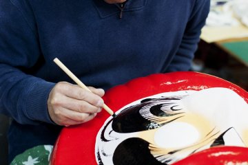 Melukis alis di atas boneka Daruma