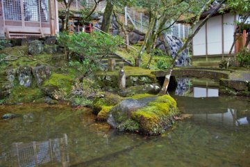 A small pond in front of a small shrine