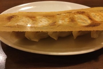 Gyoza bersayap adalah pasangan yang sempurna dengan ramen. Bagian sayapnya yang renyah adalah pembuka menuju isian daging yang lembut.