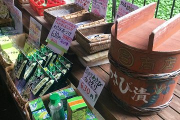 Beberapa produk wasabi dijual. Tanaman wasabi yang hijau sebagai latar belakangnya.