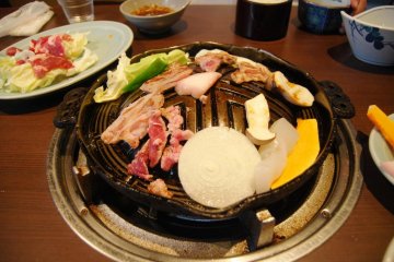 The lamb meat and some veggies are roasting nicely on this hot plate