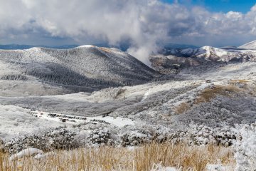Makinoto Pass, with the parking lot and observation deck as viewed from the gazebo at the foot of Mt. Hoshisho; volcanic steam rises in the distance