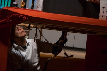 A puppeteer controlling the calligraphy marionette as part of the Karakuri Museum's puppet demonstration.