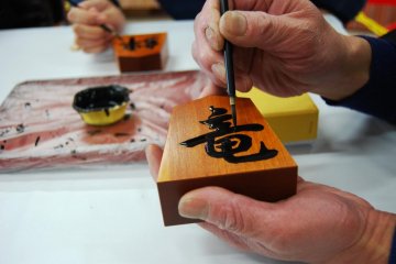 The master shogi painter applies the final touch to my shogi piece - Tendo Town, home of Japanese chess