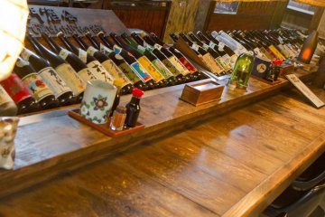 The counter bar has chairs and a sampling of sake