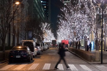 A pedestrian crosses the brightly lit street