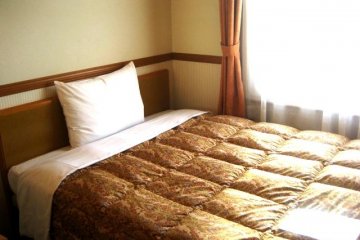 Orange Standard Issue Bed Sheets in the single room in Toyoko Inn Juso