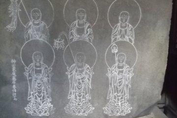 Six Buddhist figures are carved onto a large rock on an altar
