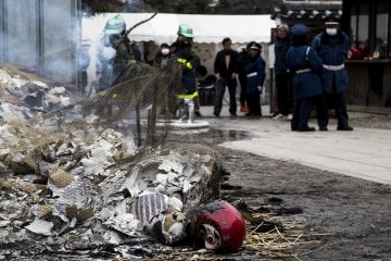 A lone Daruma doll half-burnt after most of the other ones have been turned into ashes.