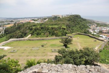 <p>The East Enclosure seen in the wooded hilltop beyond the numbered enclosures is one area of the Katsuren Castle Ruins that has not been restored</p>