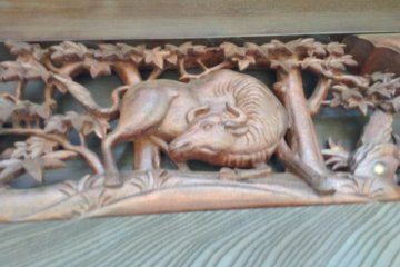 Zodiac signs are carved with magnificient detail into a wooden buidling next to the pagoda.