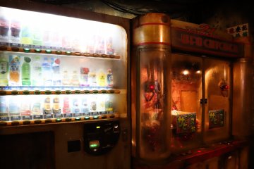 A gritty vending and claw machine are on display.