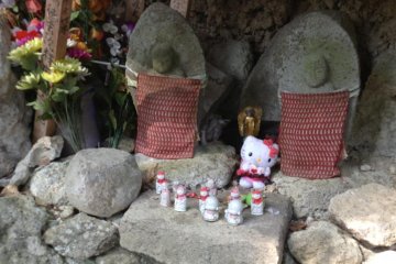 Offerings are found next to Buddhist statues. More modern offerings of toys or candy can be seen next to Japanese coins.