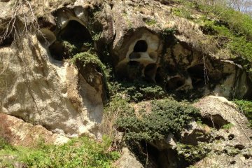 As you climb further, you exit the forest and views of the valley open up. On the cliff faces you see caves. Some seem natural, but many were enlarged by temple priests ages ago to house relics.