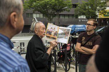 Okada showing tour members his collection of photos from his previous tours