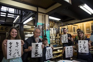 Tour members pose with Okada after they finish writing their names