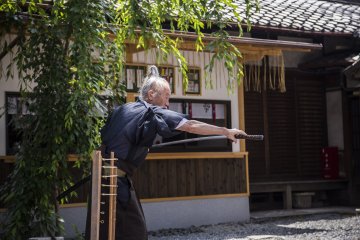 Okada drawing his katana for tour members to see