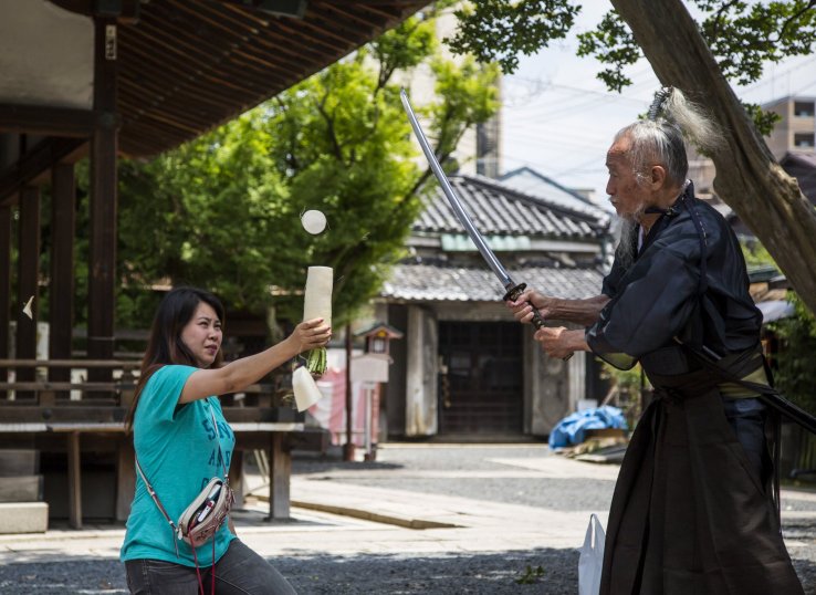 Okada slicing up a daikon held by a volunteer