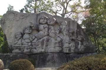 A large stone mural of children at the base of the observation hill