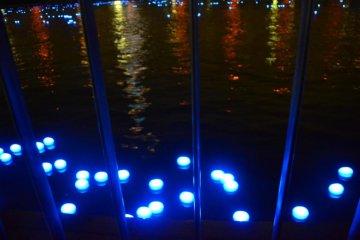 Lights passing by the edge of the river.