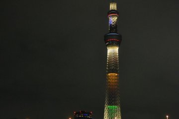 View of Tokyo Skytree behind the glowing blue Sumida River.
