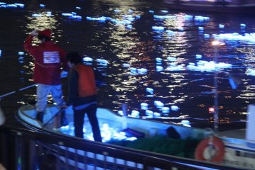 Staff in the boats scoop up the lights that have made their way down the river and bring them back to the beginning of the event area to let them float down again.