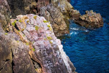 Look beyond the gates for details like the colorful rock formations with hints of leafy green descending into clear blue waters