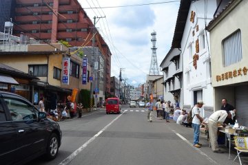 Konya-cho Street transforms into an antiques market on Sunday of every third week of the month. Notice the large warehouse of the 'Kiku no Tsukasa' brewery, a well known local sake, in the foreground on the right hand side.