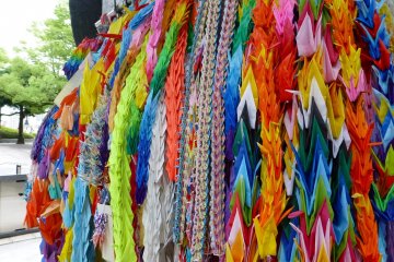 Strings of paper cranes hang from the monument