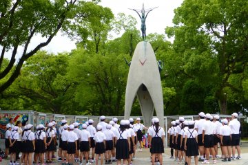 Children gather to sing a song of peace before the monument