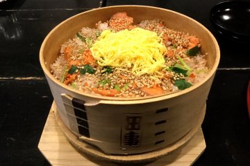 Meppameshi, rice and salmon with garnishes prepared in a bamboo 