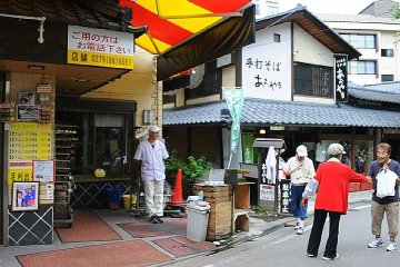 A passerby happily accepts the green tea and manju treat