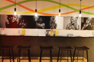 The lounge area near the drink bar has magazines and chairs.
