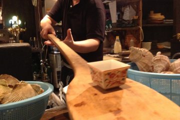 Robata style cooking involves cooking over an open flame and serving food via paddle. This is how fishermen traditionally cooked when they had few kitchen amenities.