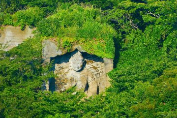 Big stone statue cut into the cliff in the forest