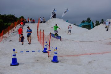 Snowboarders attempt the rail jam whilst kids enjoy sliding down the slopes on tubes and sleds