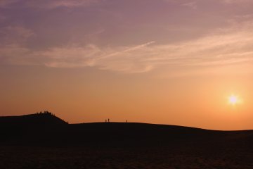 <p>Beaucoup de gens se rassemblent sur la plus grande des dunes pour regarder le soleil descendre sous l'horizon</p>