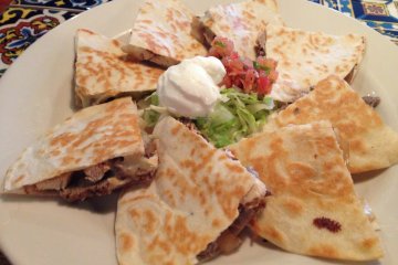Steak and Chicken fajita quesadillas topped with sour cream, lettuce and salsa Mexicana