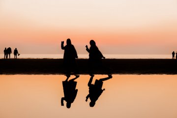 Matahari terbenam mengubah gadis-gadis muda ini menjadi siluet berwarna oranye