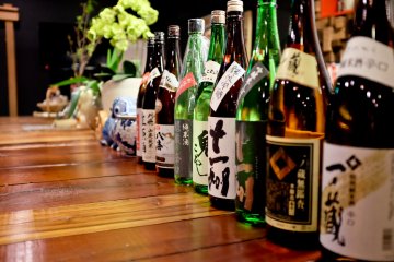 <p>Le comptoir est d&eacute;cor&eacute; avec diff&eacute;rentes bouteilles de sak&eacute; dans le plus pur style japonais</p>