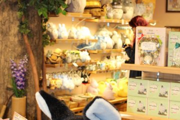 Jiji from Kiki's Delivery service, with a wall of Totoro plush toys in the background