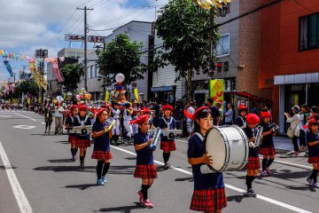 Various school marching bands parade down the street during the afternoon