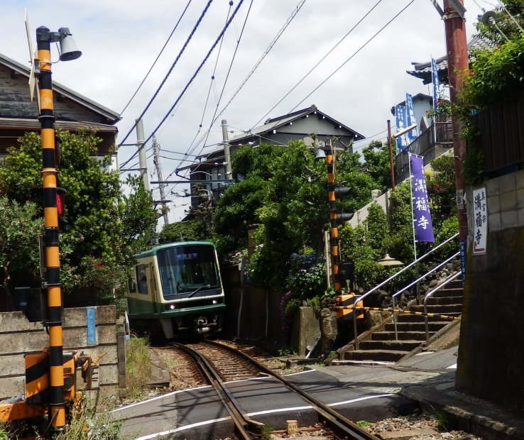 Train passing by right in front of a small temple