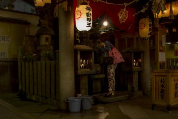A visitor prays to Fudo-myo and covers the statue with water following the tradition