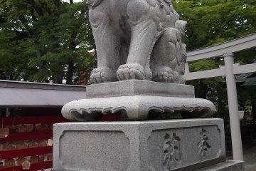 A lion stands sentinel by the shrine buildings
