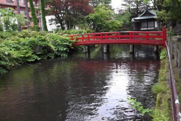 The red of the bridge stands out among the greenery