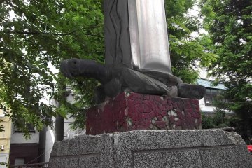 A hardy turtle supports a pillar in the parking lot by the entrance